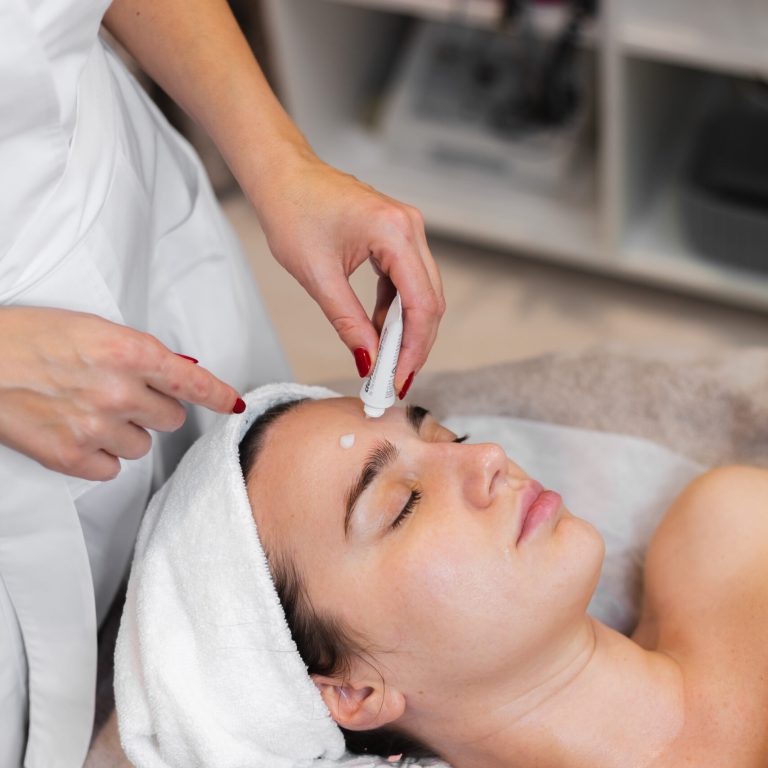 Woman client in salon receiving manual facial massage from beautician