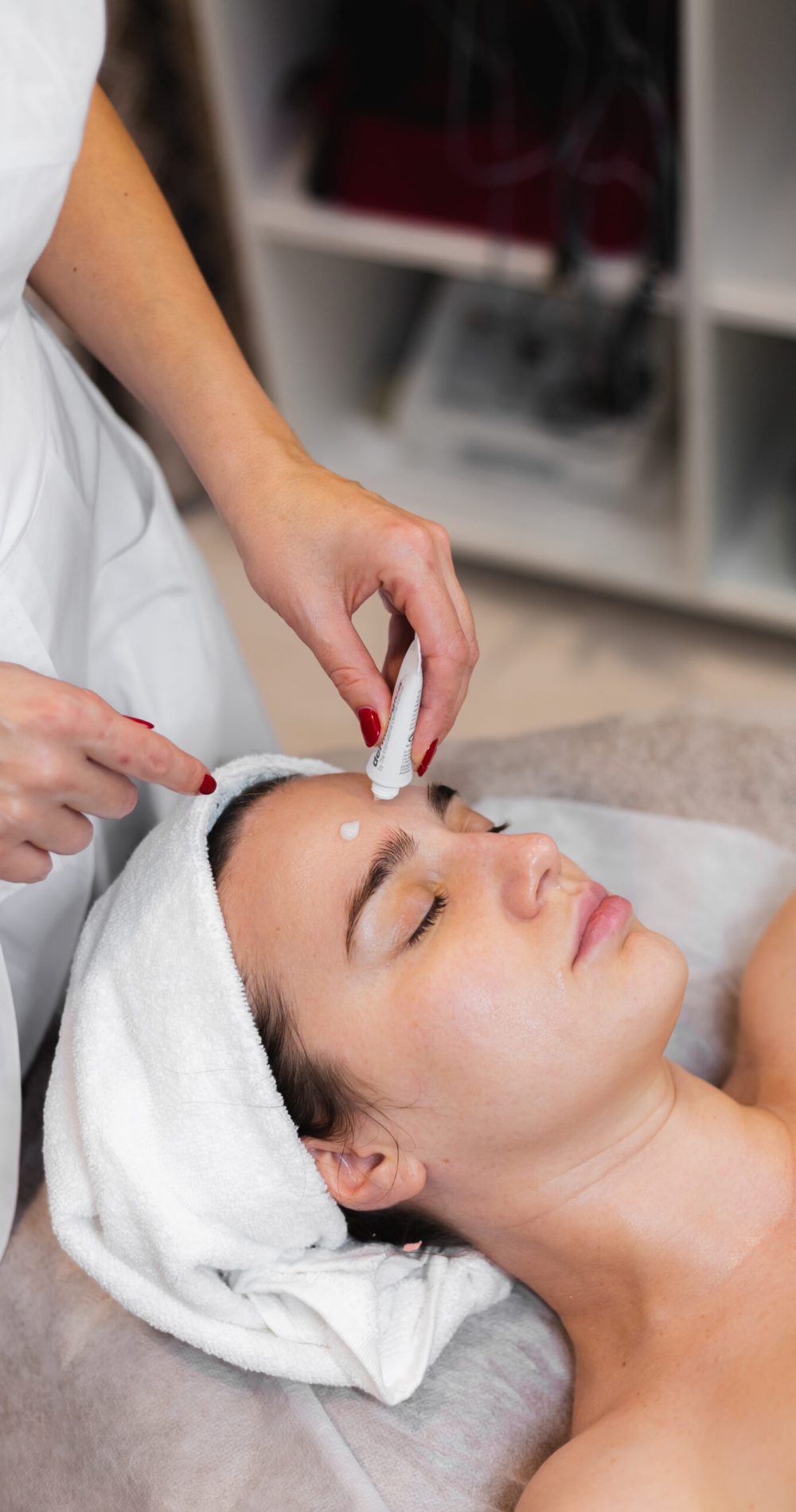 Woman client in salon receiving manual facial massage from beautician
