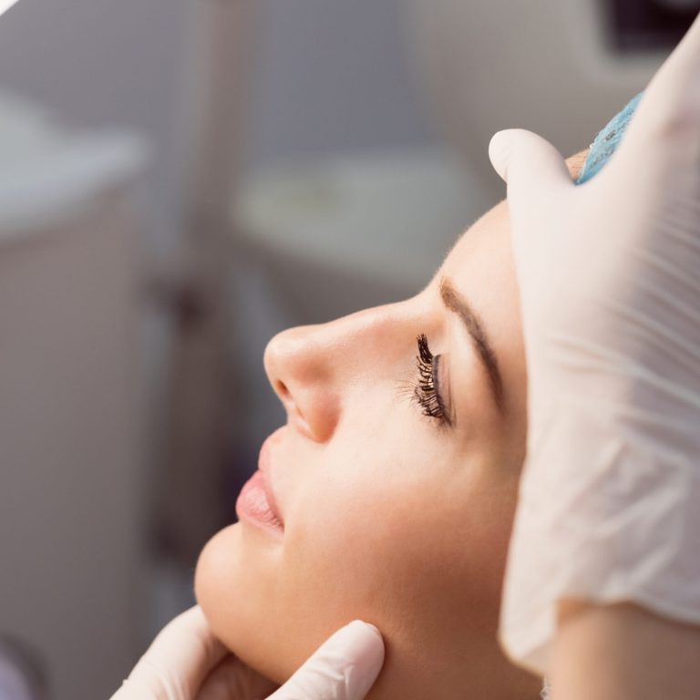 Hands of doctor examining womans face for cosmetic treatment at clinic